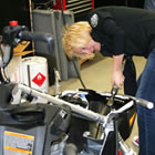 A blonde haired woman working on a snowmobile. 