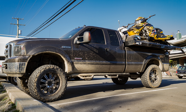 A truck with a deck and two sleds. 