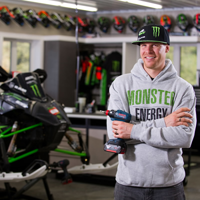Picture of Tucker Hibbert standing with Bosch drill in his hand, with snowmobile in background. 