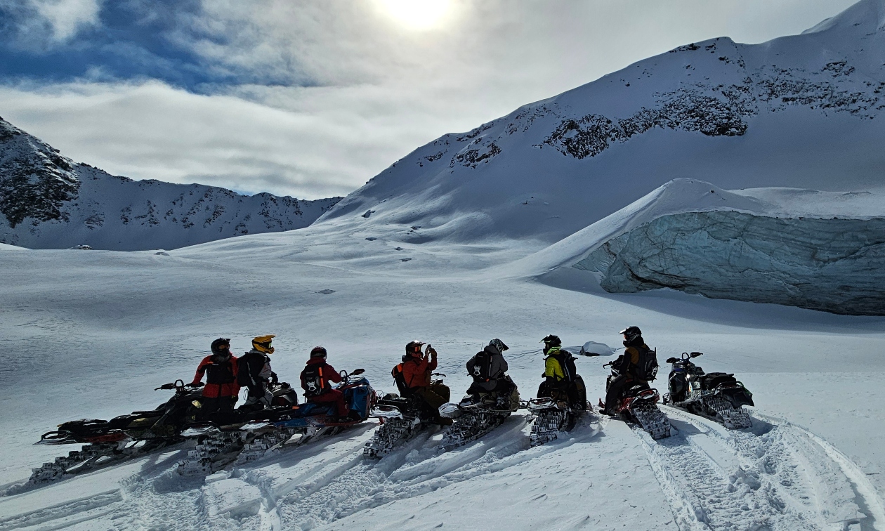 people on sleds lined up against a snowy horizon