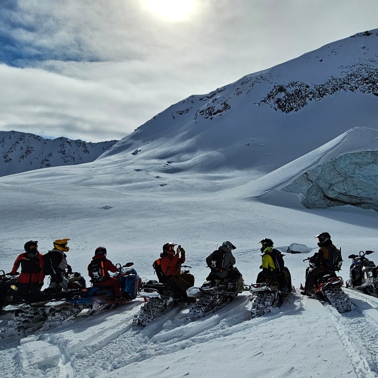people on sleds lined up against a snowy horizon