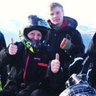 A group of snowmobilers sitting together and some of them are holding their thumbs up.