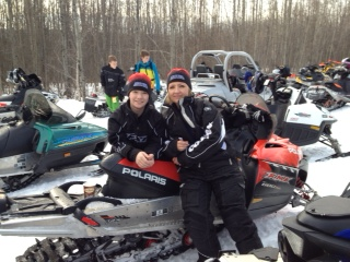 Two people standing beside a snowmobile.