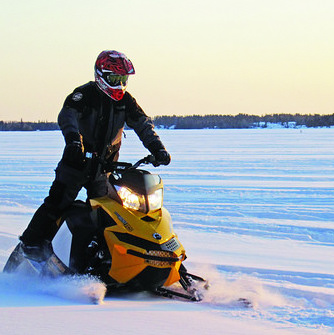 A sledder on the wide open prairie under a sky where the sun is starting to set. 