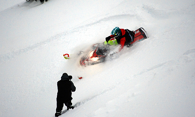 Brandon Wiesener carving on the side of a hill with a photographer. 