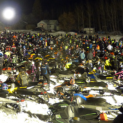 Thousands of snowmobiles parked in a field. 