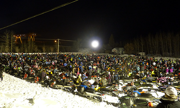 Thousands of snowmobiles parked in a field. 
